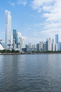 a big body of water with city in the background and a tall building on one side