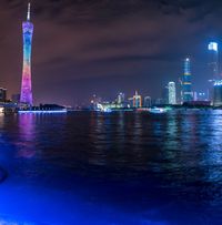 a city street with buildings and neon lights at night time in hong china as seen from an empty city highway