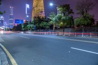 a city street with buildings and neon lights at night time in hong china as seen from an empty city highway