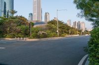 an empty road is between many buildings in the background, with a car parked and some trees