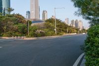 an empty road is between many buildings in the background, with a car parked and some trees