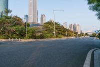 an empty road is between many buildings in the background, with a car parked and some trees