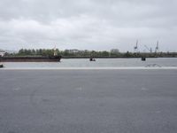 a river next to a parking lot and a boat on it's side in a body of water