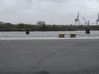 a river next to a parking lot and a boat on it's side in a body of water