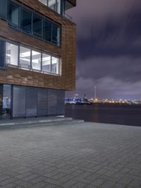a motorcycle is parked outside the building in front of the water's edge at night