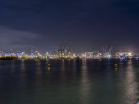 a body of water with a clock tower in the middle and lights on at the edge