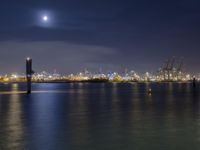 a body of water with a clock tower in the middle and lights on at the edge