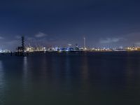 a body of water with a clock tower in the middle and lights on at the edge