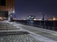 stairs and steps leading into an outdoor area near the water at night near the city