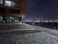 stairs and steps leading into an outdoor area near the water at night near the city