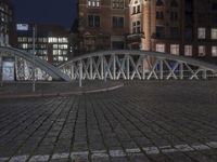 the large bridge is empty in front of the tall buildings at night time with lights on