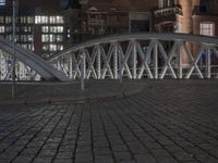 the large bridge is empty in front of the tall buildings at night time with lights on