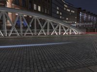 the large bridge is empty in front of the tall buildings at night time with lights on