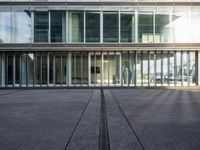 a parking lot with lots of glass windows on both sides of it and in front of the building