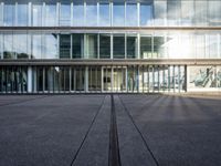 a parking lot with lots of glass windows on both sides of it and in front of the building