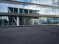 a parking lot with lots of glass windows on both sides of it and in front of the building