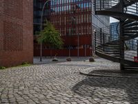 the courtyard of an industrial building has many stairs in it, and the building itself is very high with a spiral staircase to the far side