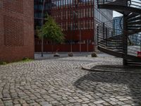 the courtyard of an industrial building has many stairs in it, and the building itself is very high with a spiral staircase to the far side