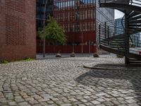 the courtyard of an industrial building has many stairs in it, and the building itself is very high with a spiral staircase to the far side