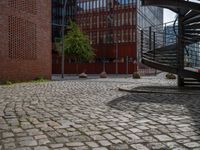 the courtyard of an industrial building has many stairs in it, and the building itself is very high with a spiral staircase to the far side