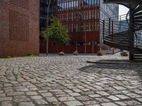 the courtyard of an industrial building has many stairs in it, and the building itself is very high with a spiral staircase to the far side