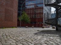 the courtyard of an industrial building has many stairs in it, and the building itself is very high with a spiral staircase to the far side