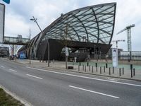 a curved structure sitting on the side of a street next to a road and traffic