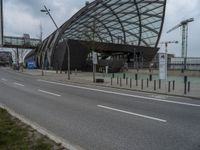 a curved structure sitting on the side of a street next to a road and traffic