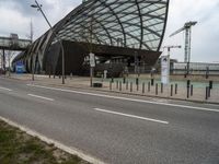 a curved structure sitting on the side of a street next to a road and traffic