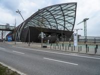 a curved structure sitting on the side of a street next to a road and traffic