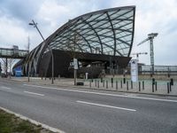 a curved structure sitting on the side of a street next to a road and traffic