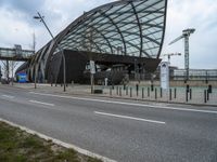 a curved structure sitting on the side of a street next to a road and traffic