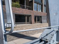 the view of some buildings from a sidewalk near another building that has a handrail on it