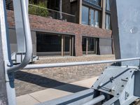 the view of some buildings from a sidewalk near another building that has a handrail on it