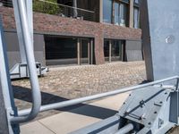 the view of some buildings from a sidewalk near another building that has a handrail on it