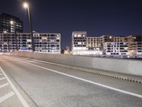 a city street with a bridge that has some cars on it at night time with streetlights