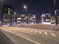 a city street with a bridge that has some cars on it at night time with streetlights