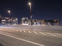 a city street with a bridge that has some cars on it at night time with streetlights