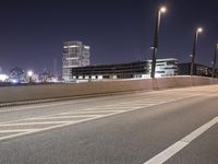 a city street with a bridge that has some cars on it at night time with streetlights