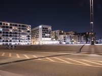 a city street with a bridge that has some cars on it at night time with streetlights