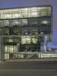 large glass building at night in front of stairs and a walkway leading to various levels