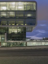 large glass building at night in front of stairs and a walkway leading to various levels