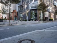 the street in the city has buildings on both sides and trees around it on either side