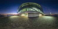 a circular building is lit up at night with a large windowed front area on one side