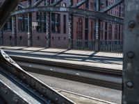 a man is standing on the rail road tracks looking at another person walking near a building with lots of windows