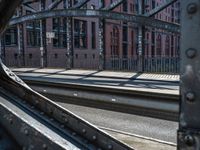 a man is standing on the rail road tracks looking at another person walking near a building with lots of windows