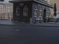 a woman on a bike driving down the street past an outdoor seating area and restaurant