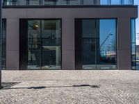 a view of the sidewalk and the entrance to the building with the reflection of another