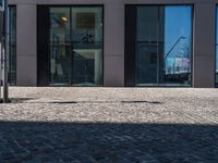 a view of the sidewalk and the entrance to the building with the reflection of another