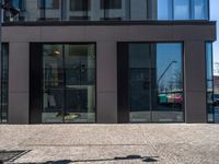 a view of the sidewalk and the entrance to the building with the reflection of another